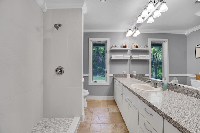 full bathroom featuring toilet, vanity, tiled shower, stone tile flooring, and crown molding