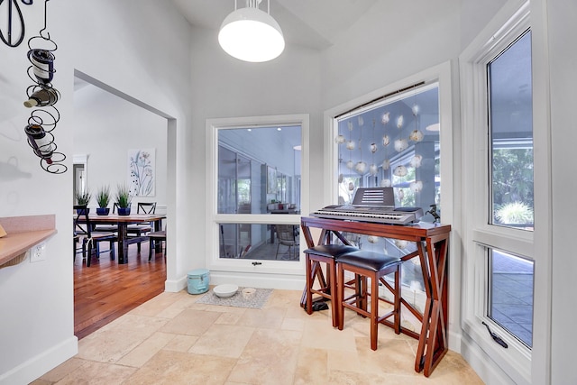 interior space featuring baseboards, stone tile flooring, and a healthy amount of sunlight