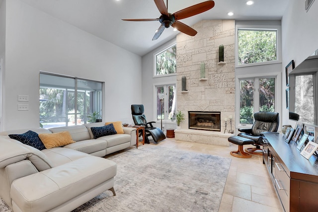 living room with high vaulted ceiling, a wealth of natural light, visible vents, and a stone fireplace