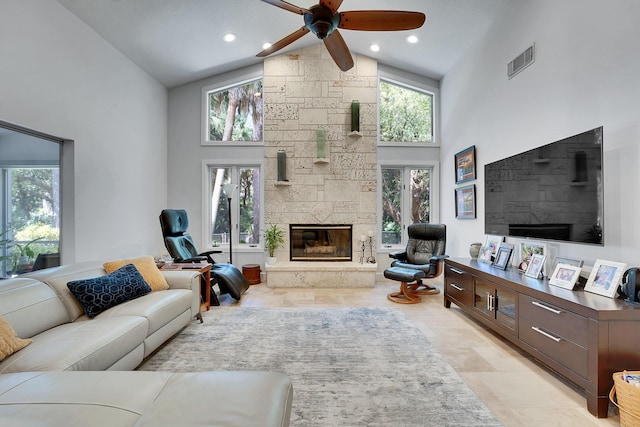 living room featuring high vaulted ceiling, ceiling fan, visible vents, and a stone fireplace