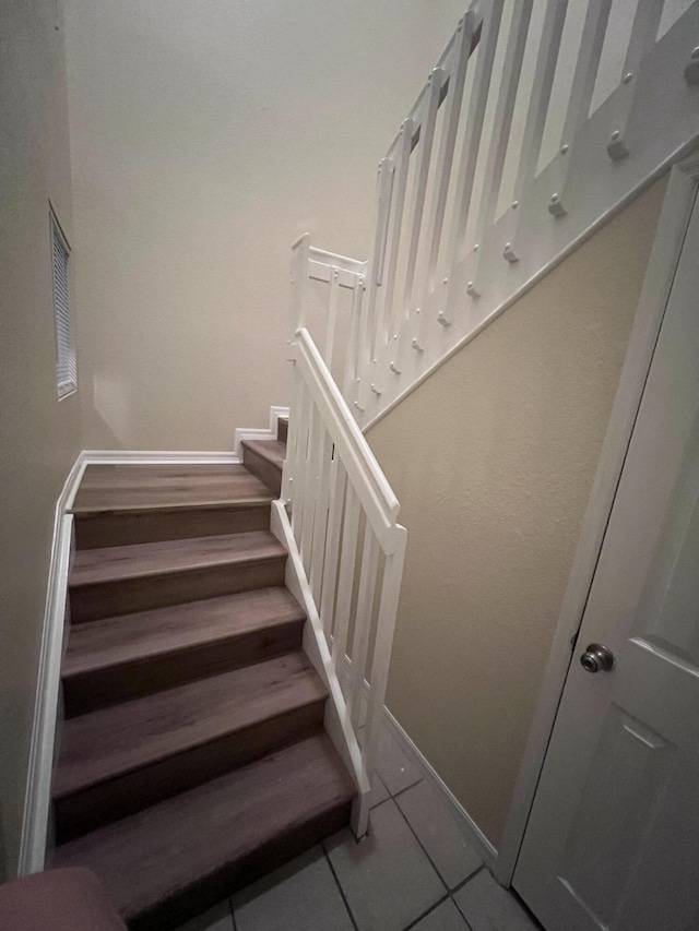 stairs with baseboards and tile patterned floors