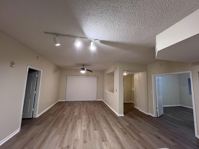 bonus room with ceiling fan, a textured ceiling, baseboards, and wood finished floors