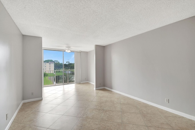 unfurnished room with expansive windows, light tile patterned flooring, a ceiling fan, and baseboards