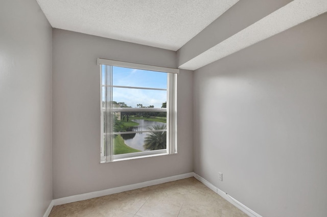 unfurnished room featuring a textured ceiling, light tile patterned floors, and baseboards