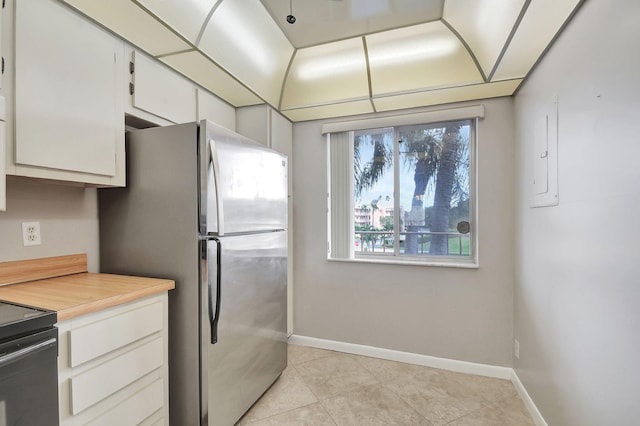 kitchen featuring light countertops, black range with electric stovetop, freestanding refrigerator, white cabinets, and light tile patterned flooring