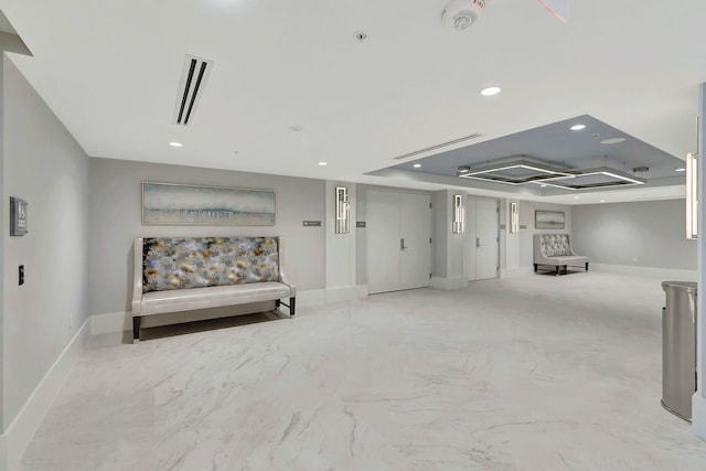 interior space featuring recessed lighting, a raised ceiling, and baseboards