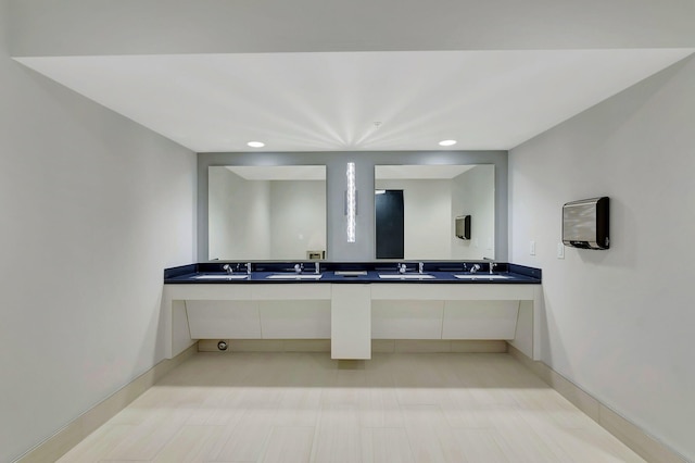 bathroom featuring double vanity, a sink, and baseboards