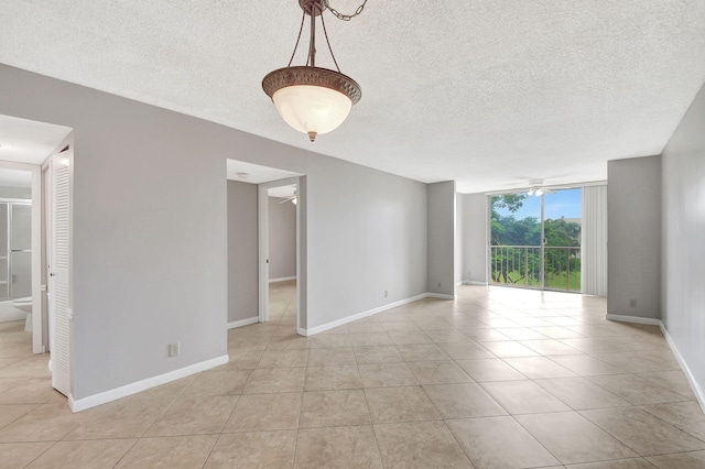 empty room with baseboards, floor to ceiling windows, a ceiling fan, and light tile patterned flooring