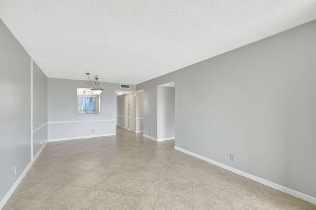 empty room featuring visible vents, a textured ceiling, baseboards, and light tile patterned flooring