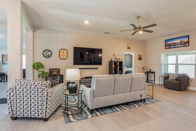 living area featuring wood finished floors, a ceiling fan, baseboards, and visible vents