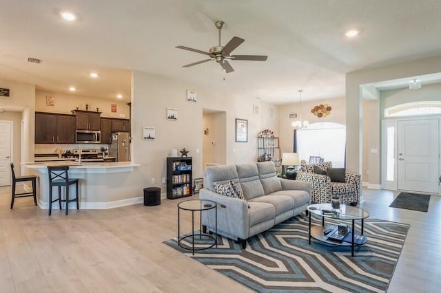 living room with light wood-type flooring, visible vents, a ceiling fan, recessed lighting, and baseboards