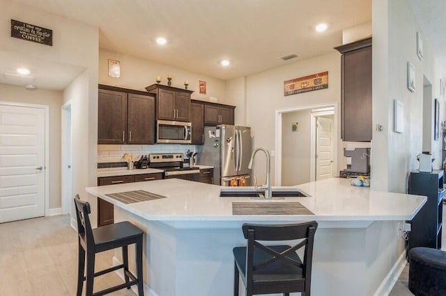 kitchen featuring visible vents, dark brown cabinets, light countertops, stainless steel appliances, and a sink