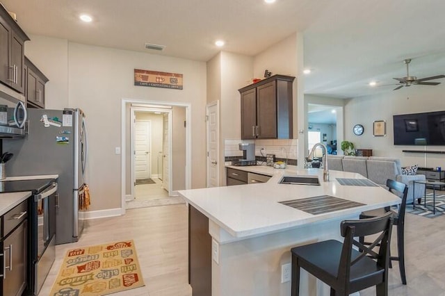 kitchen featuring a sink, stainless steel microwave, range with electric stovetop, and light countertops