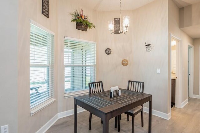 dining area featuring a notable chandelier, baseboards, and light wood finished floors