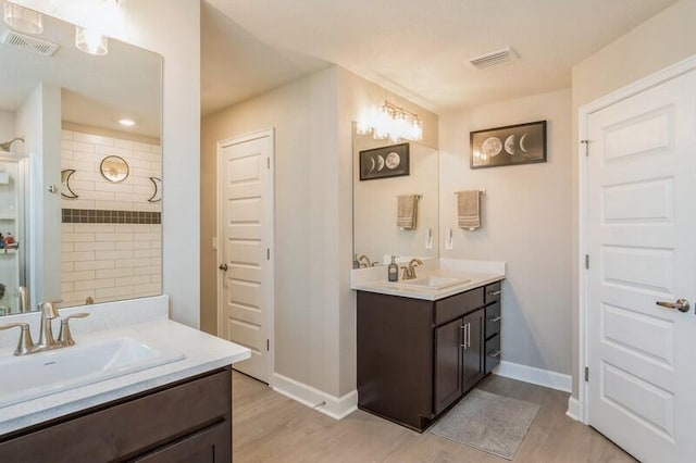 bathroom featuring two vanities, wood finished floors, visible vents, and a sink