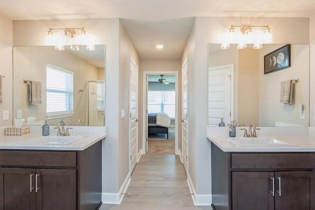 ensuite bathroom featuring a shower stall, baseboards, and a sink