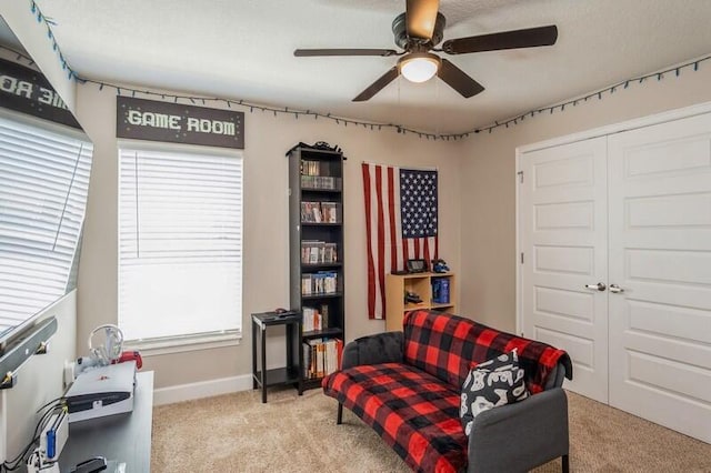 sitting room with light carpet, baseboards, and ceiling fan