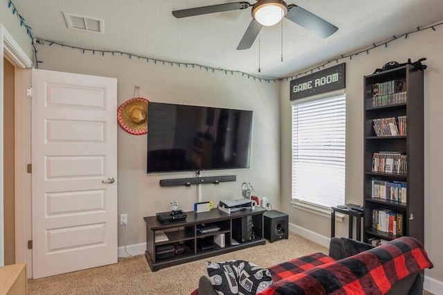 living area with visible vents, baseboards, carpet, and a ceiling fan