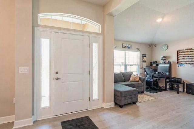 entrance foyer featuring light wood finished floors, baseboards, and vaulted ceiling