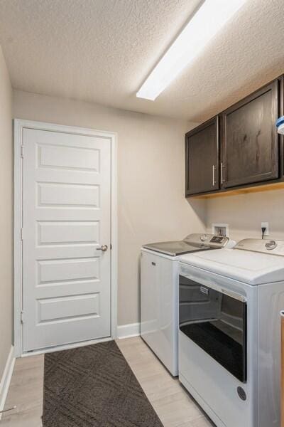 washroom with baseboards, light wood-style flooring, cabinet space, a textured ceiling, and independent washer and dryer