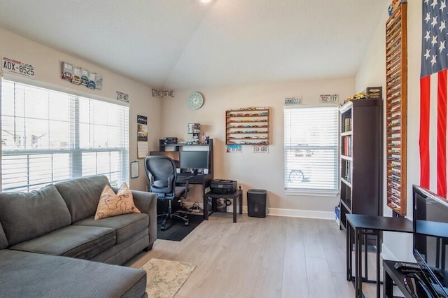 office space with lofted ceiling, plenty of natural light, baseboards, and light wood-type flooring