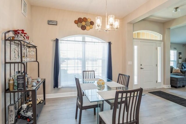 dining area with baseboards, a notable chandelier, and wood finished floors