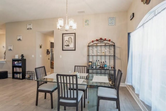 dining room featuring wood finished floors, baseboards, and a chandelier