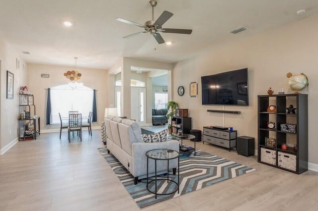 living room featuring a ceiling fan, visible vents, light wood finished floors, and baseboards