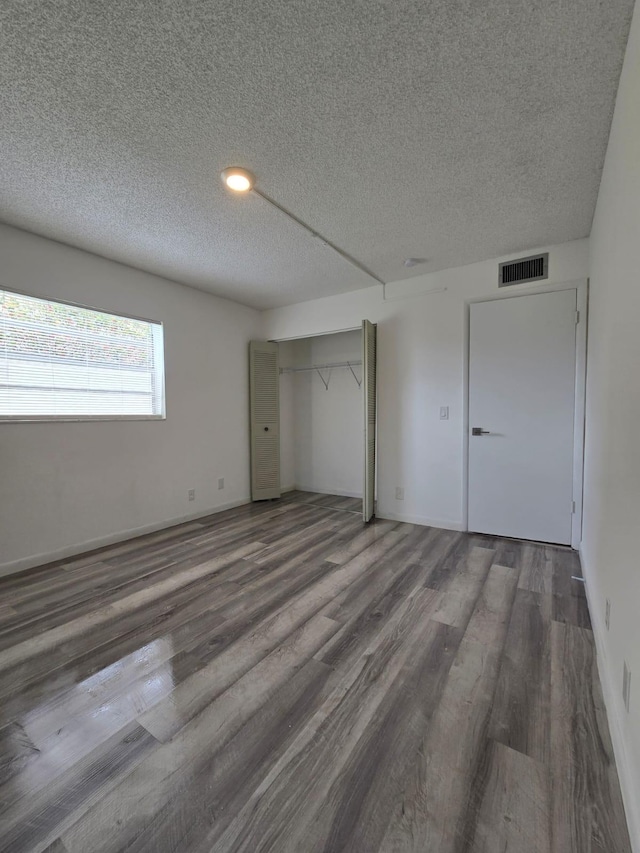 774 Burgundy Q, Delray Beach, FL 33484 - unfurnished bedroom featuring a closet, a textured ceiling, wood finished floors, and visible vents