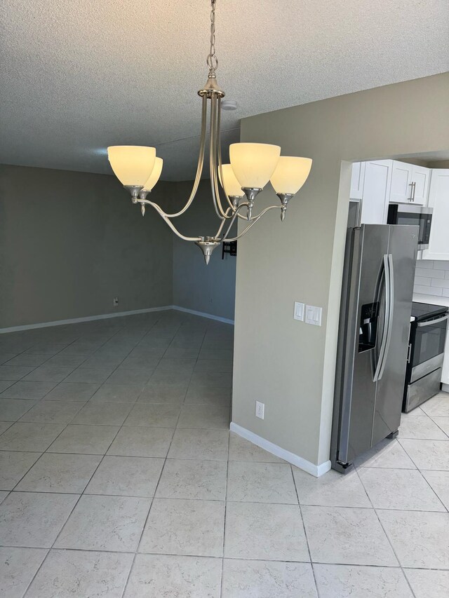 774 Burgundy Q, Delray Beach, FL 33484 - interior space with an inviting chandelier, a textured ceiling, stainless steel appliances, white cabinetry, and light tile patterned floors