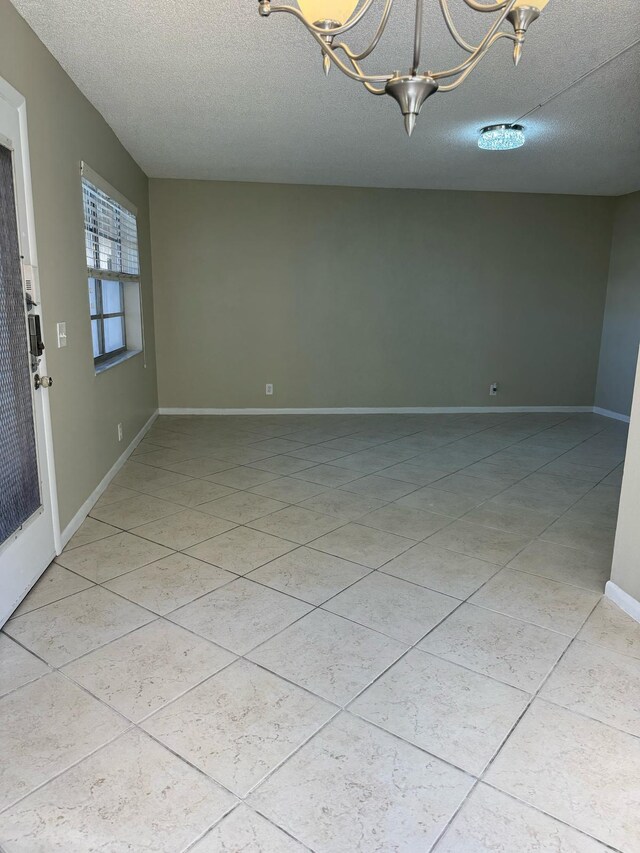 774 Burgundy Q, Delray Beach, FL 33484 - unfurnished room featuring baseboards, light tile patterned flooring, a textured ceiling, and a notable chandelier