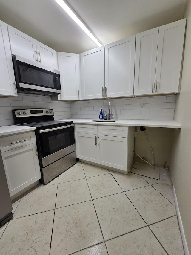 kitchen with a sink, stainless steel appliances, backsplash, and light tile patterned flooring