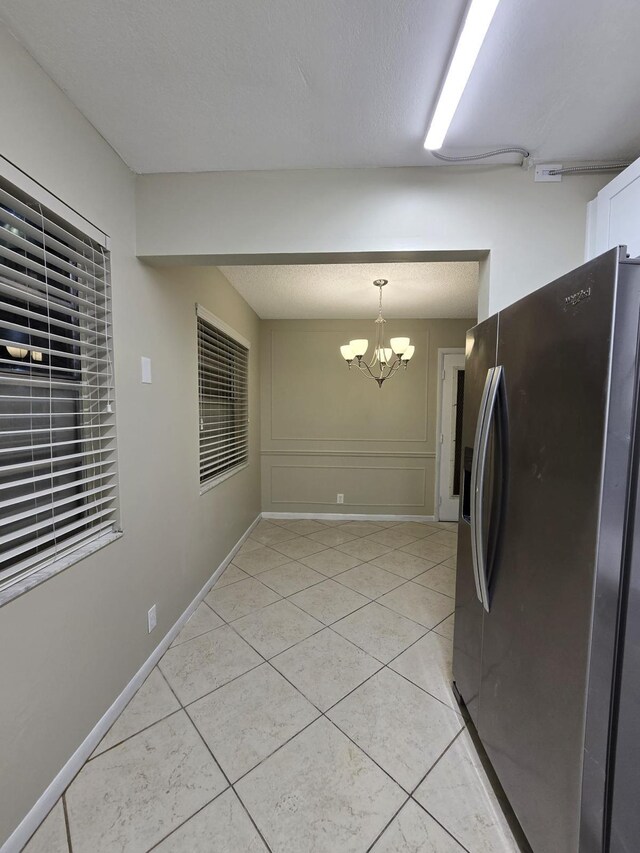 774 Burgundy Q, Delray Beach, FL 33484 - interior space featuring stainless steel refrigerator with ice dispenser, pendant lighting, light tile patterned flooring, a notable chandelier, and white cabinetry