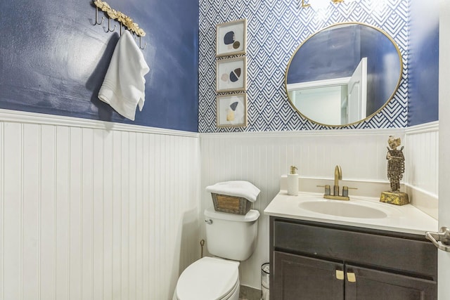 half bath with toilet, wainscoting, and vanity