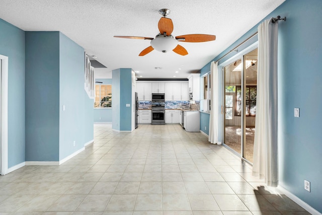 unfurnished living room featuring light tile patterned floors, a textured ceiling, baseboards, and a ceiling fan