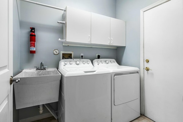 clothes washing area with washing machine and clothes dryer, cabinet space, and a sink