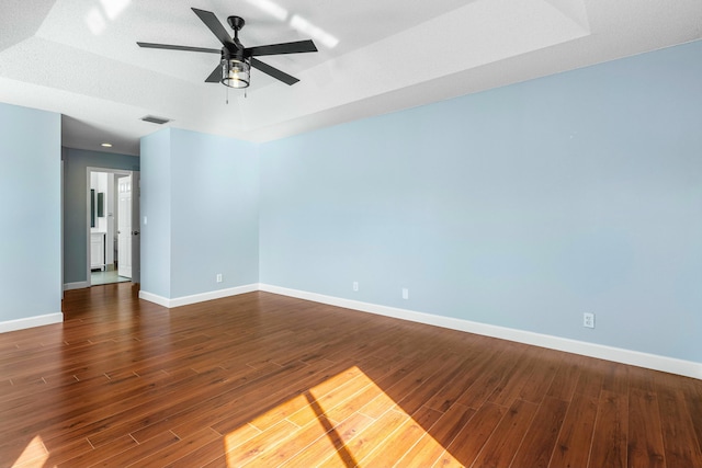 spare room with visible vents, ceiling fan, baseboards, and dark wood-style flooring