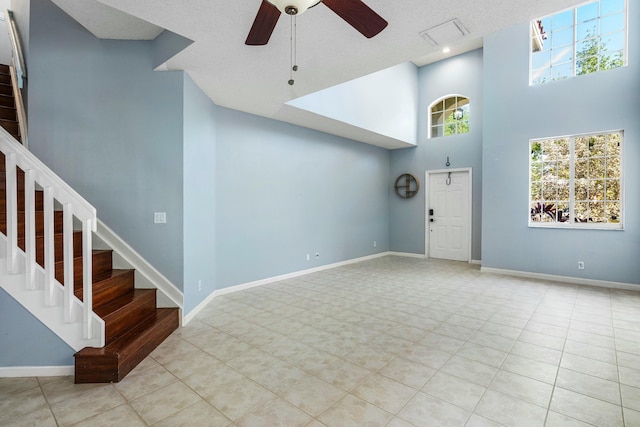 unfurnished living room with stairway, baseboards, and a towering ceiling