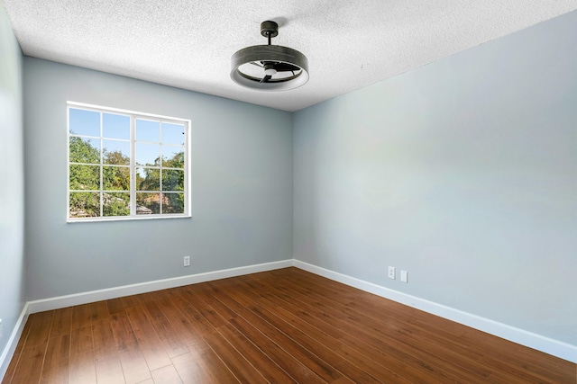 unfurnished room featuring baseboards, dark wood-type flooring, and a textured ceiling