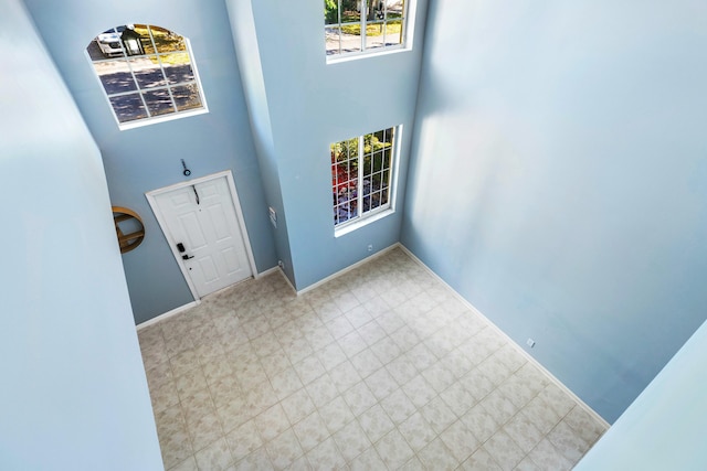 entryway featuring baseboards and a towering ceiling