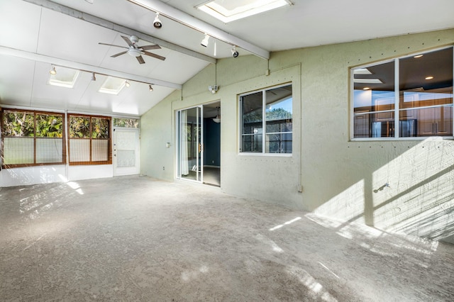 unfurnished sunroom with lofted ceiling with skylight, track lighting, and ceiling fan