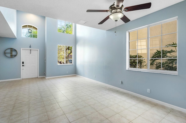 empty room with tile patterned flooring, a healthy amount of sunlight, baseboards, and ceiling fan