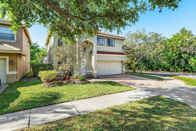 mediterranean / spanish house with stucco siding, driveway, a front yard, an attached garage, and a tiled roof