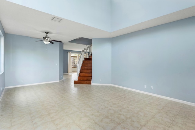 unfurnished living room with stairs, visible vents, a ceiling fan, and baseboards