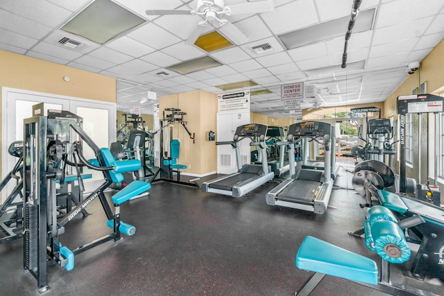 gym featuring a ceiling fan, a paneled ceiling, and visible vents