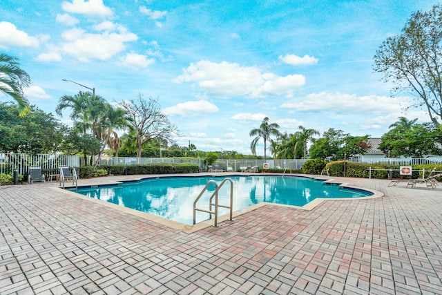 pool with a patio area and fence