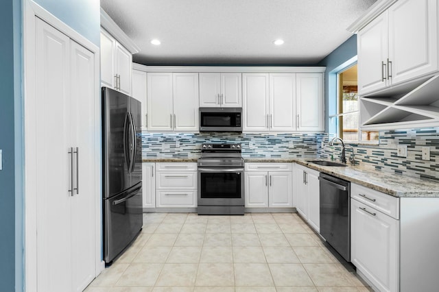 kitchen with a sink, backsplash, white cabinetry, and stainless steel appliances