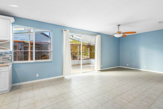 spare room with light tile patterned floors, visible vents, baseboards, ceiling fan, and a textured ceiling