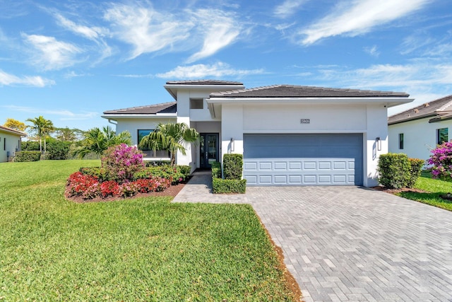 view of front facade with a front lawn, a tile roof, stucco siding, decorative driveway, and an attached garage