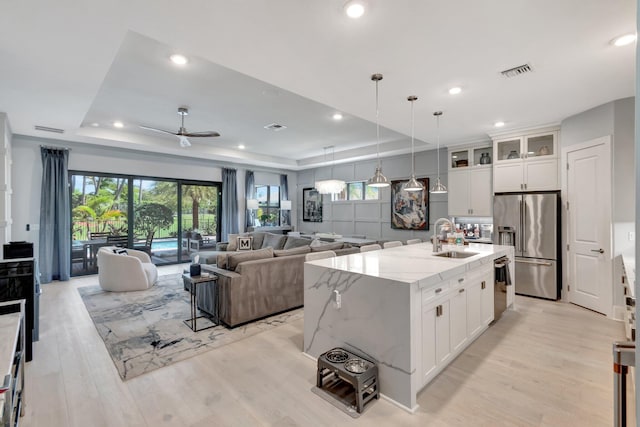 kitchen with visible vents, a sink, white cabinets, appliances with stainless steel finishes, and a raised ceiling